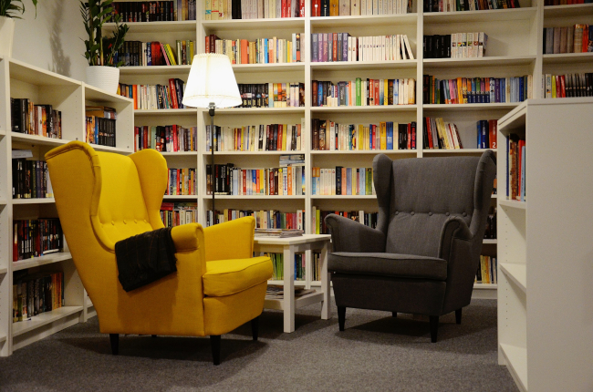 Wnętrze Biblioteki Publicznej we Wronkach. Widoczne regały z książkami oraz dwa fotele - żółty i czarny 