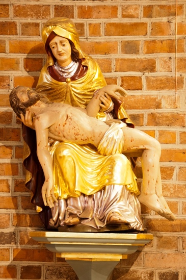 Rzeźba we wronieckiej farze - pieta. Matka Boża ubrana w złota suknię trzyma na kolana ch ciło Chrystusa. 